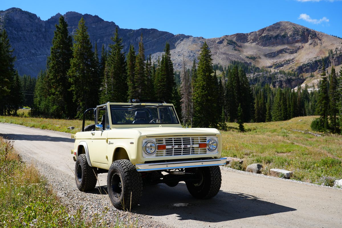 Baby Palomino from the front three-quarter, parked on a gravel mountain road beneath rocky peaks